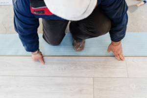 Vinyl Plank Flooring being set by a man in a white hard hat in Coral Gables.