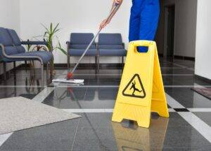 Close-up Of Man Cleaning The Floor With Yellow Wet Floor Sign for a Janitorial Service in Coral Gables, FL 
